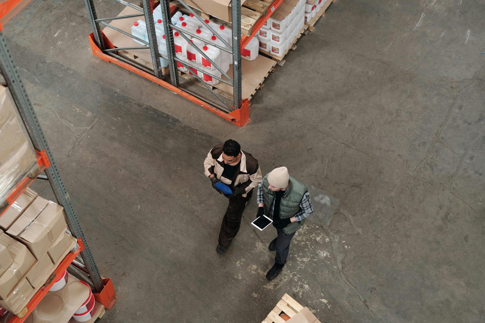 Workers reviewing operations beside a forklift in a warehouse