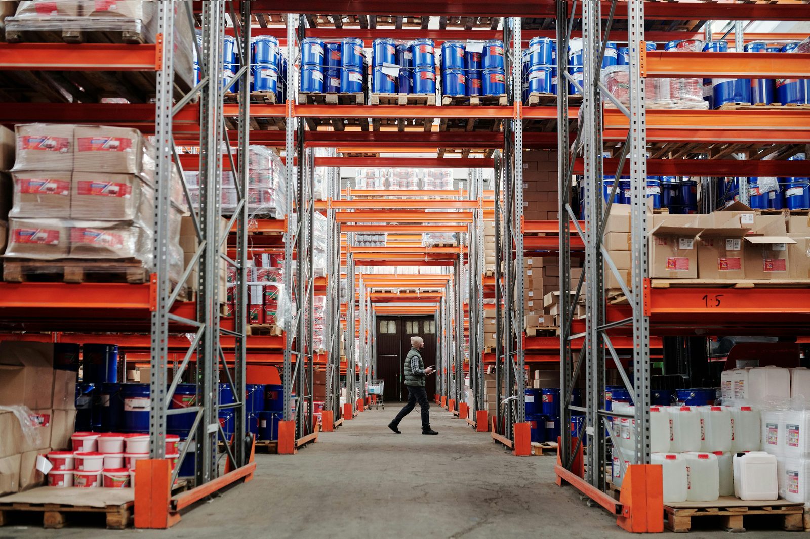 Worker walking the aisle of a stocked warehouse